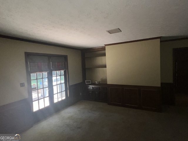 carpeted empty room with crown molding and a textured ceiling