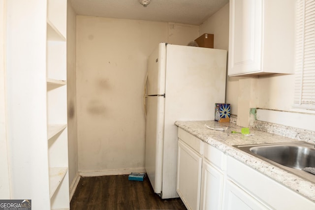 kitchen with light stone countertops, a textured ceiling, white cabinets, dark wood-type flooring, and white refrigerator