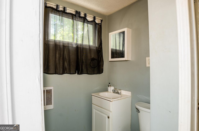 bathroom with toilet, a textured ceiling, vanity, and heating unit