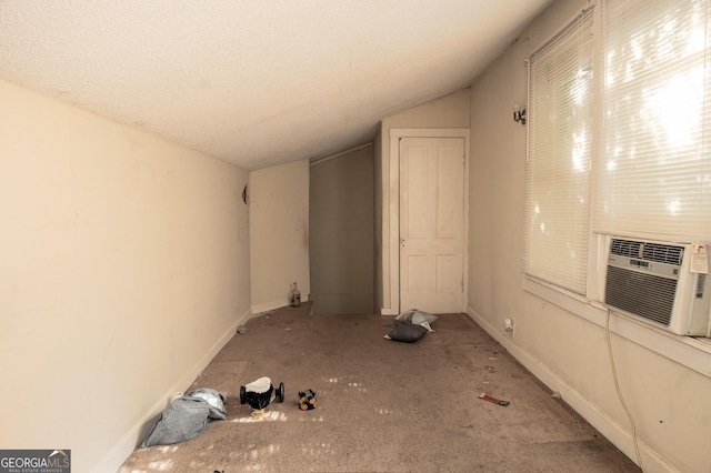 interior space with a textured ceiling, cooling unit, vaulted ceiling, and carpet floors