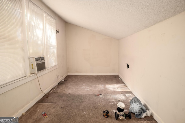 carpeted empty room with a textured ceiling and lofted ceiling