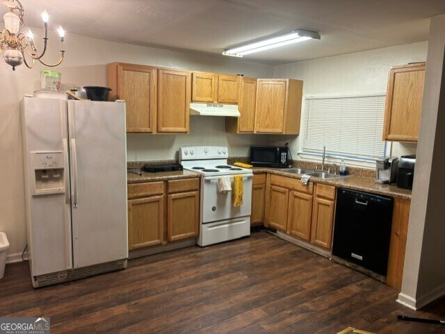 kitchen with black appliances, sink, a chandelier, and dark hardwood / wood-style flooring