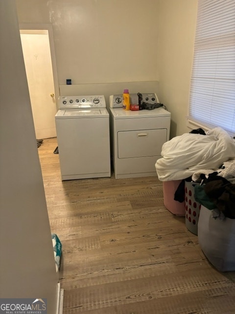 laundry area with washing machine and clothes dryer and light hardwood / wood-style floors