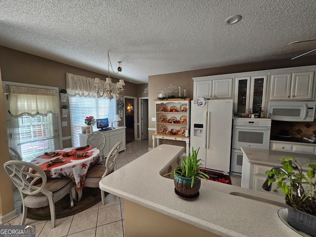 kitchen featuring white cabinets, hanging light fixtures, white appliances, and light tile patterned floors