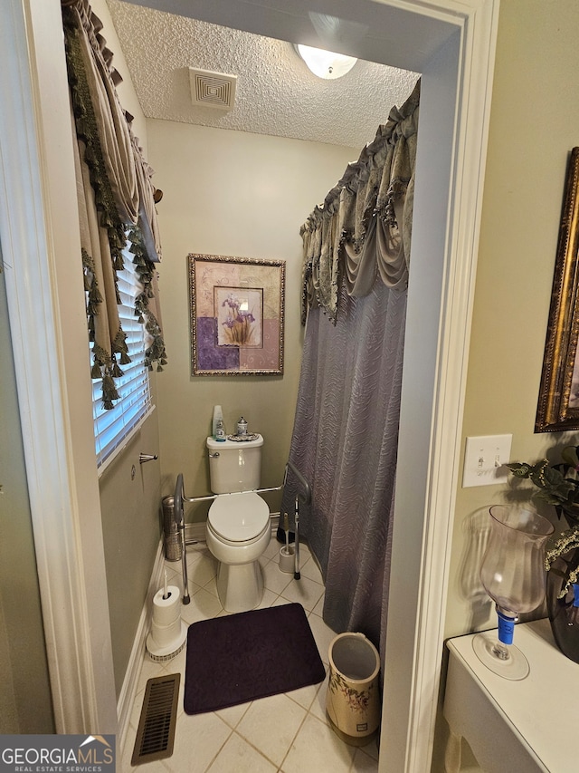 bathroom with toilet, a textured ceiling, and tile patterned floors