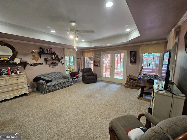 carpeted living room featuring french doors, crown molding, a tray ceiling, and ceiling fan