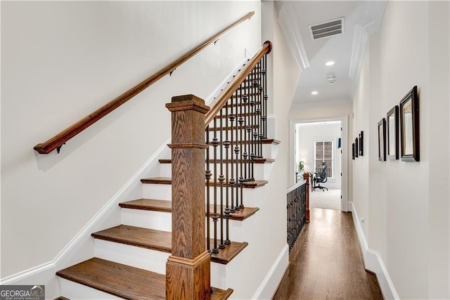 staircase with ornamental molding and hardwood / wood-style floors