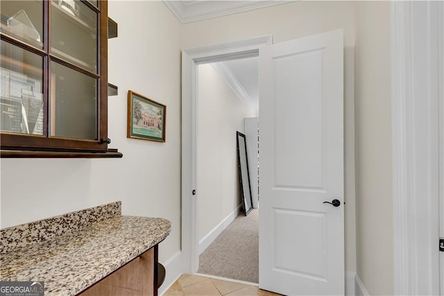 hallway featuring ornamental molding and light tile patterned floors