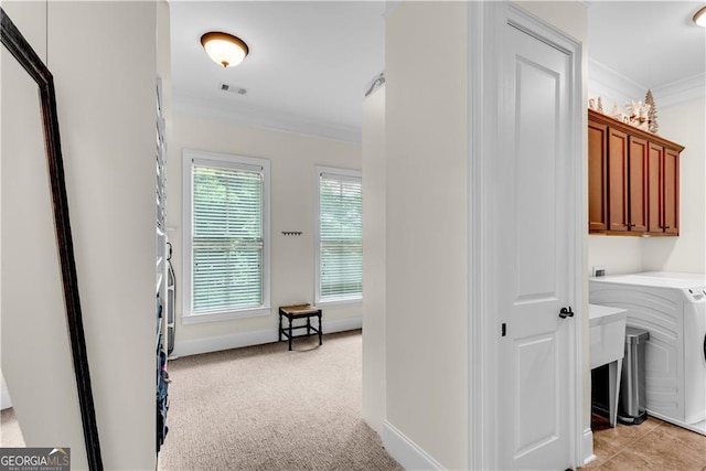 laundry room featuring crown molding, washer / clothes dryer, light carpet, and cabinets