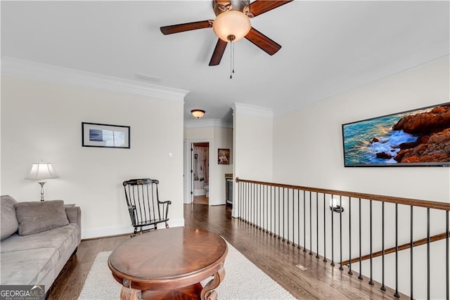 living room with ornamental molding, dark wood-type flooring, and ceiling fan