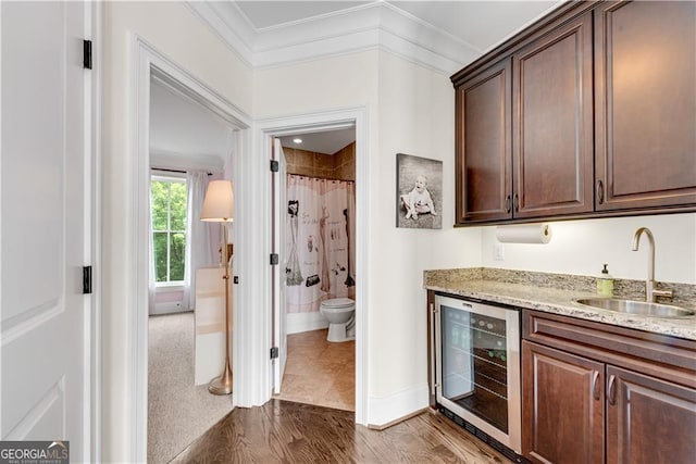 kitchen featuring sink, crown molding, wood-type flooring, and beverage cooler