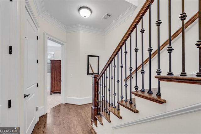 staircase featuring hardwood / wood-style floors and crown molding