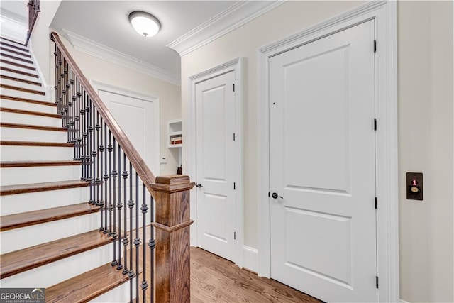 entryway featuring ornamental molding and light hardwood / wood-style flooring