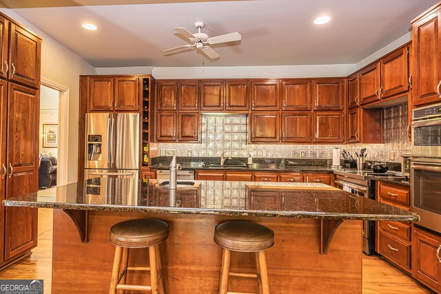 kitchen featuring a kitchen island with sink, decorative backsplash, appliances with stainless steel finishes, and sink