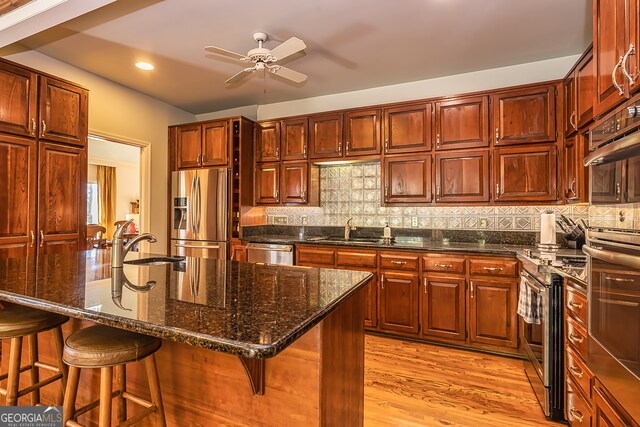 kitchen featuring a kitchen island with sink, stainless steel appliances, sink, and backsplash