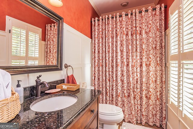 bathroom with toilet, vanity, and crown molding