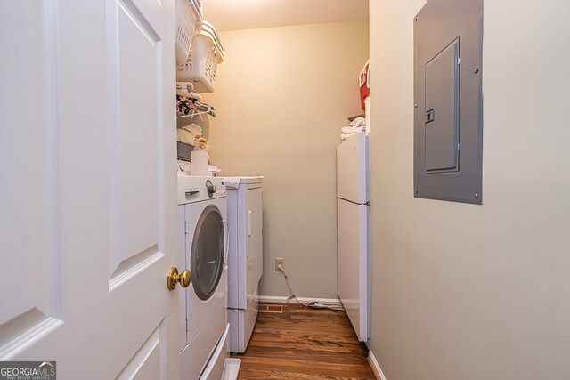 washroom with dark wood-type flooring, washing machine and dryer, and electric panel