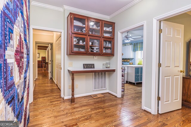 corridor with ornamental molding and light hardwood / wood-style floors