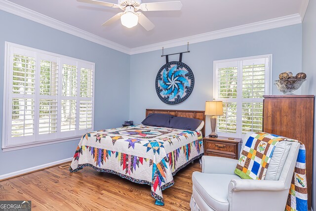 bedroom featuring ornamental molding, multiple windows, hardwood / wood-style floors, and ceiling fan