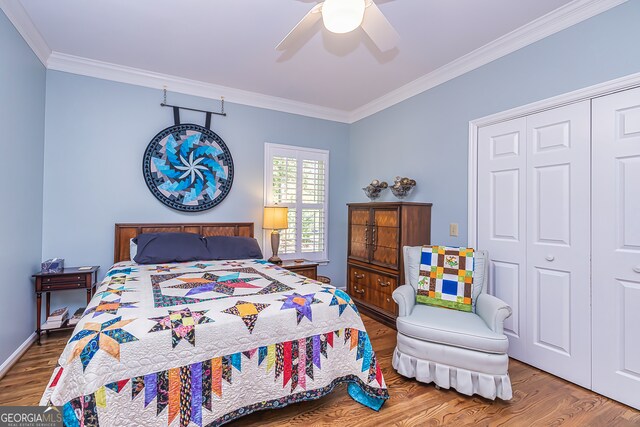 bedroom featuring hardwood / wood-style floors, ceiling fan, crown molding, and a closet