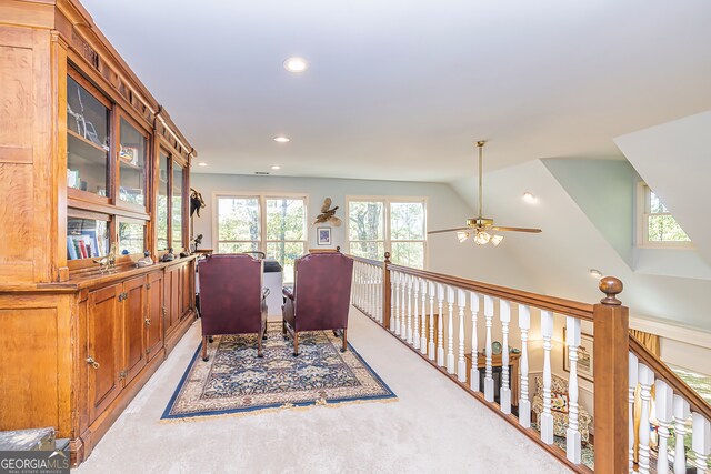 living area featuring ceiling fan, light carpet, and lofted ceiling