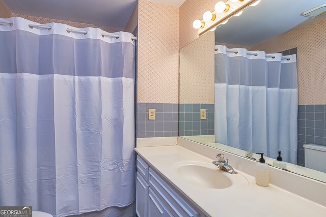 bathroom with tile walls, vanity, and toilet