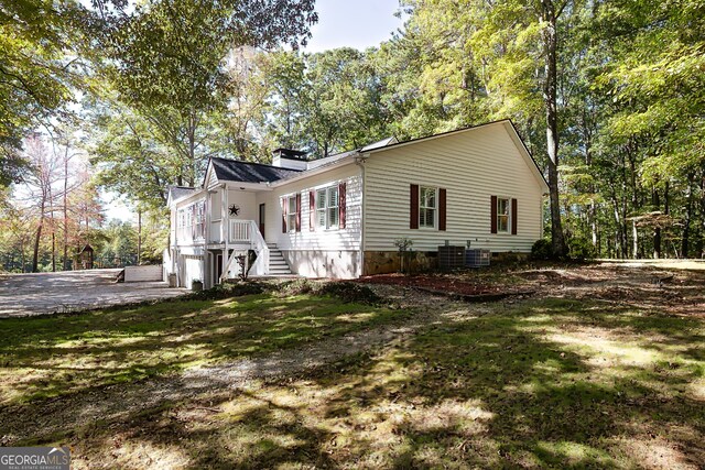 view of home's exterior featuring a garage, central AC unit, and a yard