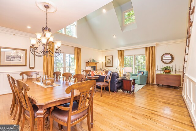 dining space featuring a healthy amount of sunlight, light hardwood / wood-style flooring, high vaulted ceiling, and a notable chandelier