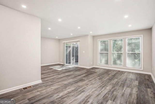 unfurnished room with a healthy amount of sunlight and dark wood-type flooring