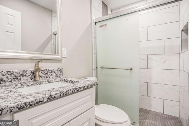 bathroom featuring a shower with door, vanity, and toilet