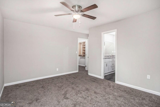 unfurnished bedroom featuring a spacious closet, ceiling fan, a closet, and dark carpet