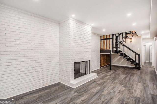 unfurnished living room with brick wall, a fireplace, and hardwood / wood-style flooring