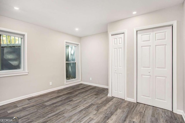 unfurnished bedroom featuring two closets and dark hardwood / wood-style floors