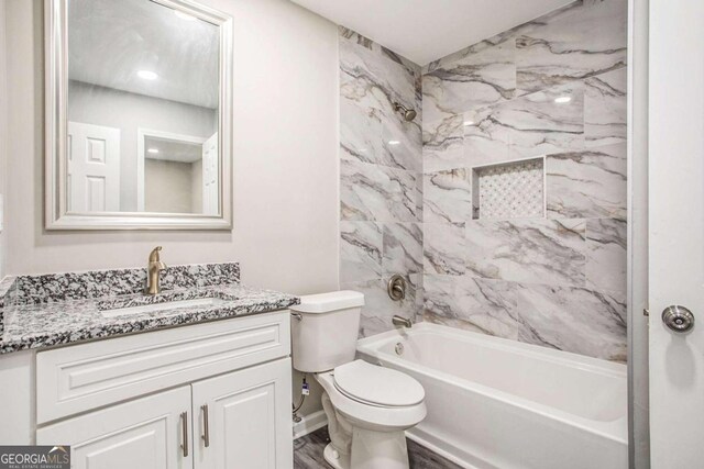 full bathroom featuring vanity, tiled shower / bath, hardwood / wood-style floors, and toilet