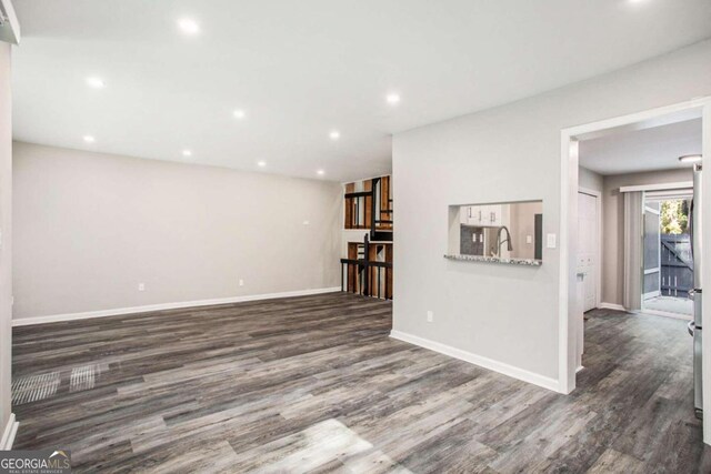 unfurnished living room with sink and dark wood-type flooring