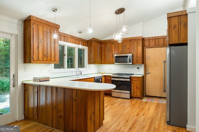 kitchen with lofted ceiling, hanging light fixtures, kitchen peninsula, plenty of natural light, and appliances with stainless steel finishes