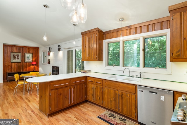 kitchen with hanging light fixtures, stainless steel dishwasher, sink, and vaulted ceiling