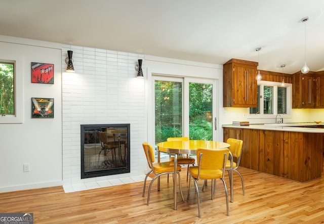 dining area featuring a large fireplace, a healthy amount of sunlight, and light wood-type flooring