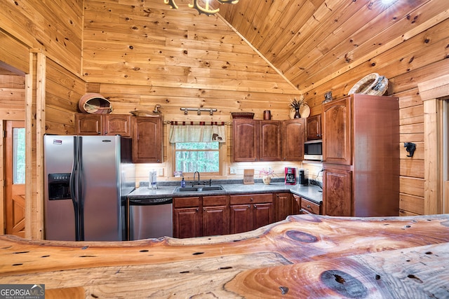 kitchen featuring high vaulted ceiling, wood walls, stainless steel appliances, and sink