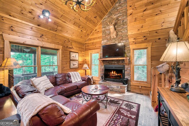 living room featuring high vaulted ceiling, wooden ceiling, light hardwood / wood-style flooring, wood walls, and a fireplace