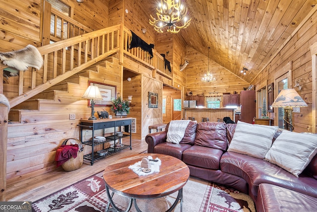 living room featuring a notable chandelier, high vaulted ceiling, light hardwood / wood-style floors, and wood walls