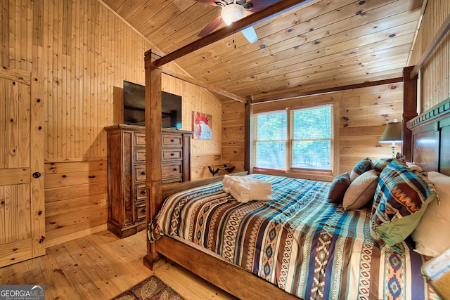 bedroom featuring light hardwood / wood-style floors, ceiling fan, wooden walls, and vaulted ceiling