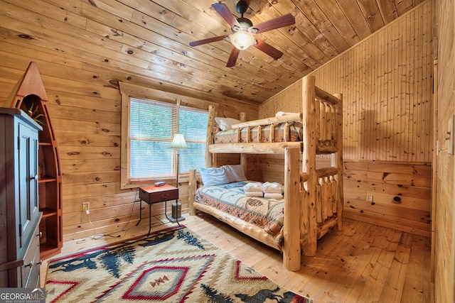 bedroom featuring lofted ceiling, wood ceiling, ceiling fan, light hardwood / wood-style flooring, and wood walls