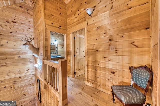 sitting room with wooden walls and light hardwood / wood-style flooring