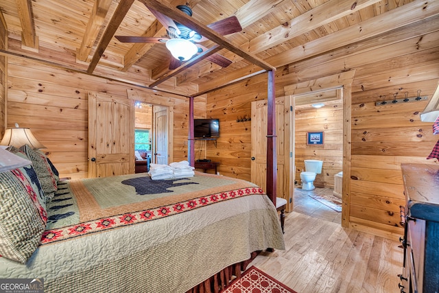 bedroom with wood walls, light hardwood / wood-style floors, beamed ceiling, wooden ceiling, and connected bathroom