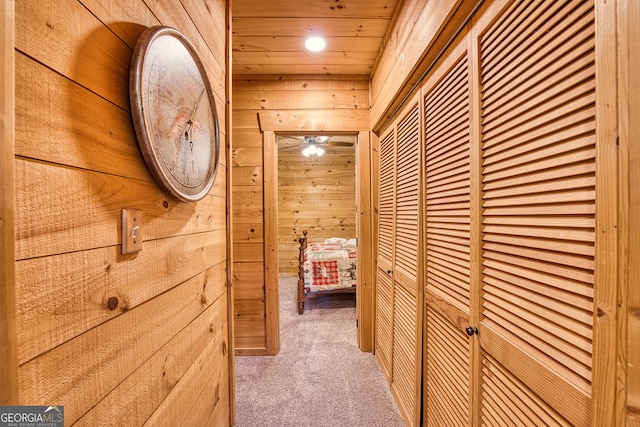 hall with wood walls, carpet, and wooden ceiling