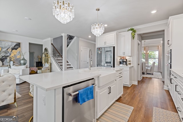 kitchen with appliances with stainless steel finishes, hanging light fixtures, hardwood / wood-style floors, white cabinets, and a center island with sink