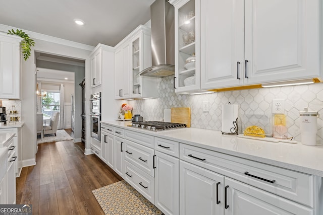 kitchen with wall chimney range hood, stainless steel appliances, dark hardwood / wood-style flooring, white cabinetry, and tasteful backsplash