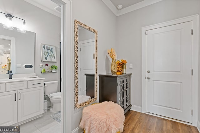 bathroom with vanity, toilet, crown molding, and hardwood / wood-style floors