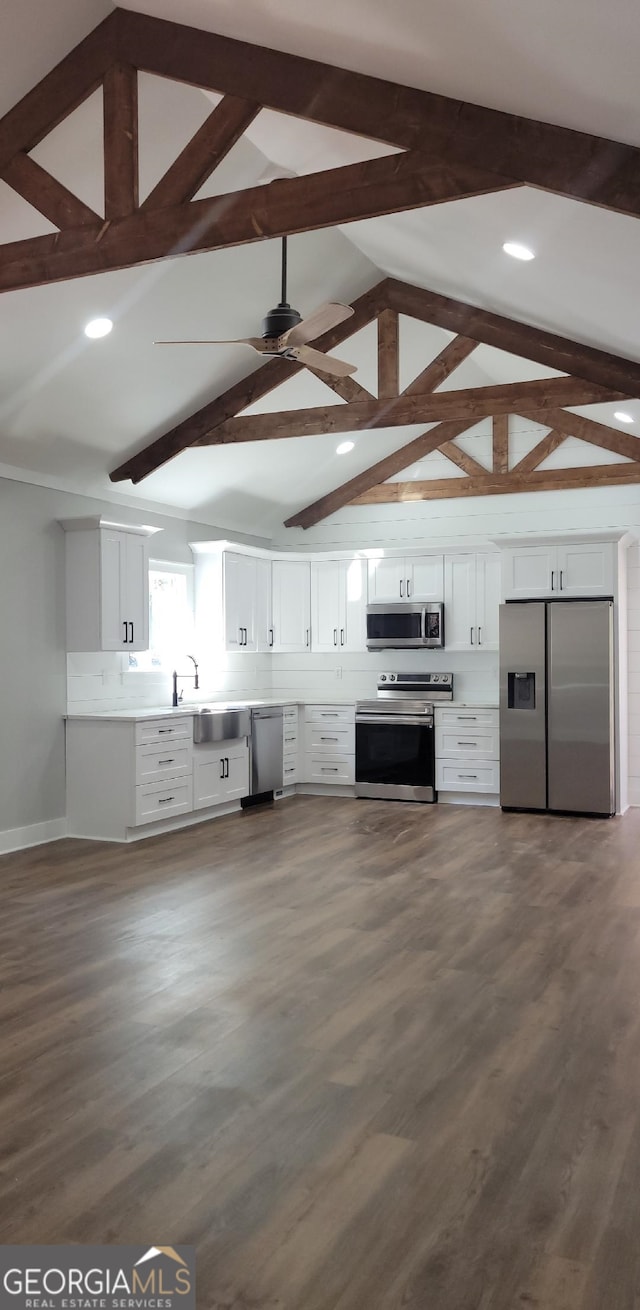 kitchen with lofted ceiling with beams, stainless steel appliances, dark hardwood / wood-style floors, and white cabinets